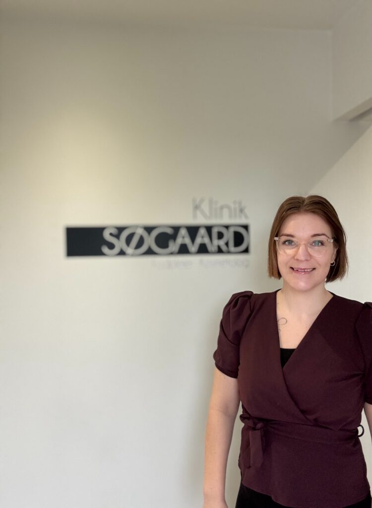 Majbritt Søgaard Nilsson foran skiltet til Klinik Søgaard